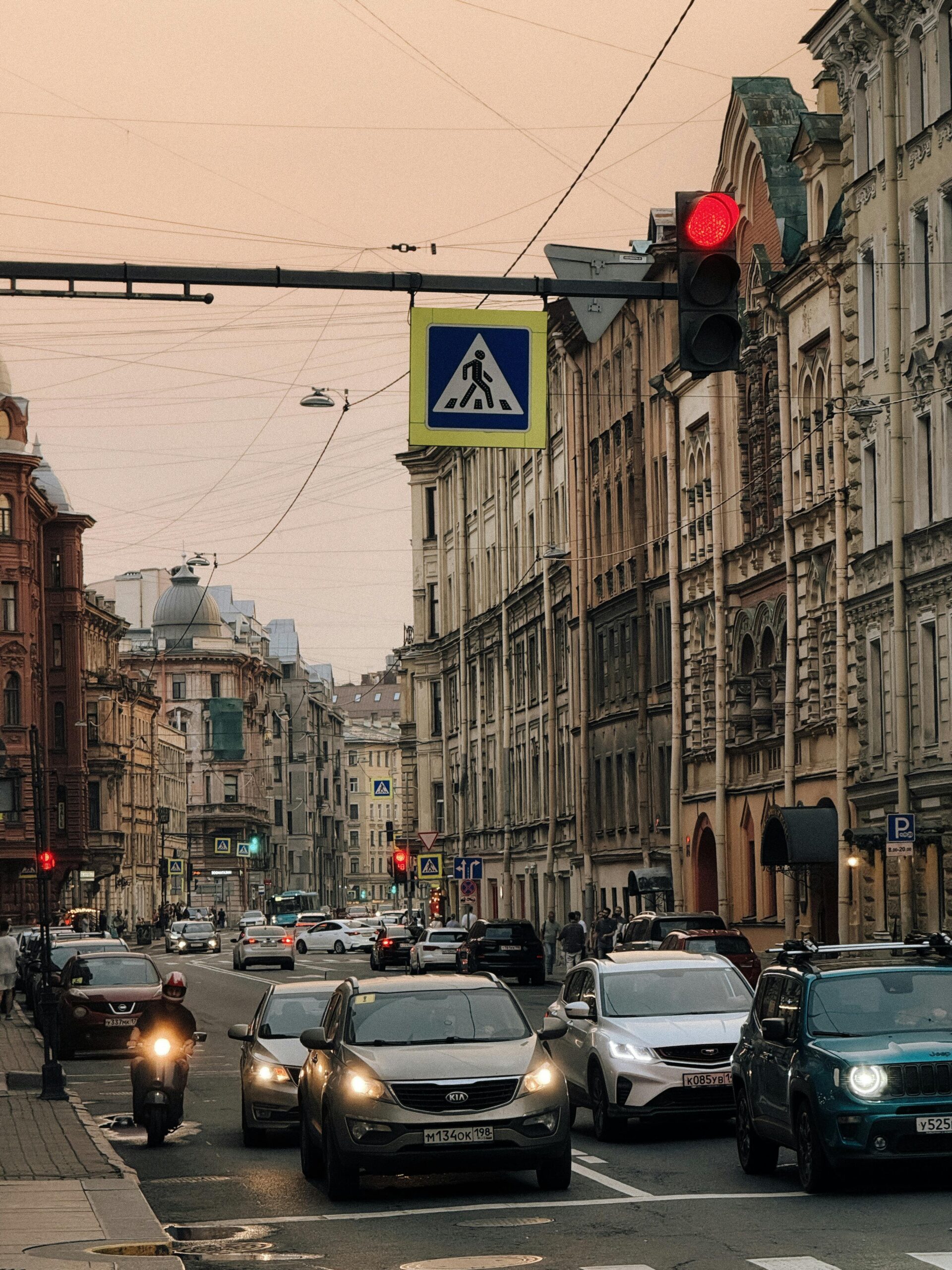 City street bustling with traffic under a sunset sky, featuring historic architecture and vibrant atmosphere.